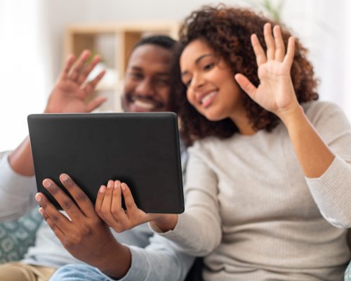 technology, communication and people concept - close up of happy couple with tablet pc computer having video call at home