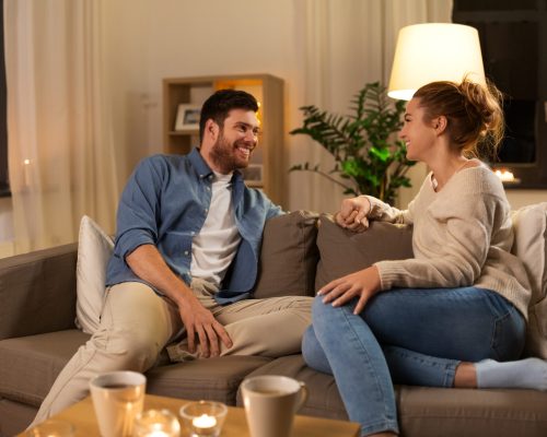 leisure and people concept - happy couple talking at home in evening