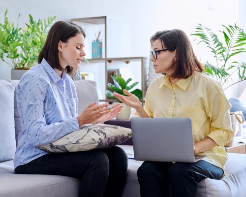 Young woman patient on individual therapy in psychologists office. Mature female counselor listening taking notes talking. Psychology, psychiatry, treatment, mental health concept